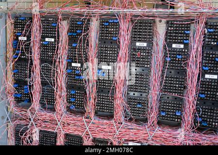 An outdoor telephone box with tangled wires and corrosion, haphazardly ...