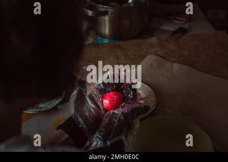 Girl in plastic gloves paints red Easter egg Stock Photo