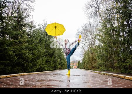 Ageing and health, Older Adults Healthy People. Care and support needs of older people. Happy senior woman in yellow rain coat with yellow umbrella Stock Photo