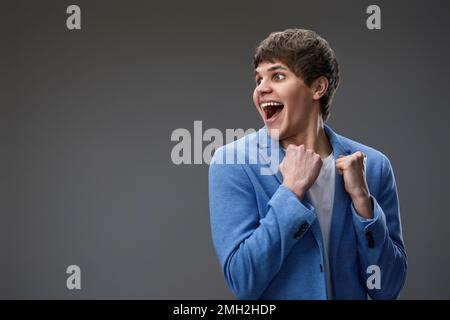 very excited young man showing victory gesture holding fists raising Stock Photo