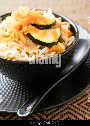 Asian soup with mie noodles, TVP, cabbage, zucchini and shredded carrots. Stock Photo