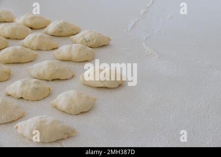 Homemade buns with potatoes made from yeast dough on white countertop as they are being made Stock Photo