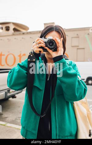 woman in green coat taking photos with vintage Canon film camera Stock Photo