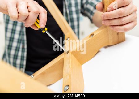 Self-assembly furniture concept. The young man himself assembling chairs Stock Photo