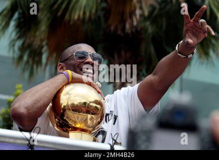 Kobe Bryant holds both the Lakers 2010 NBA Championship trophy and the 2010 NBA  Finals trophy.