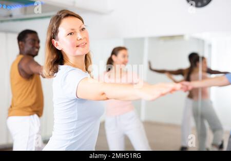Smiling young adult couples dancing together in pairs and practicing movements in modern choreography class Stock Photo