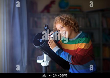 Little boy looking at stars through telescope. Child watching night sky and moon. Astronomy and science for young explorer kid. Stock Photo