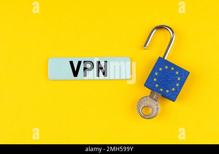 On a yellow surface, an open padlock with the image of the flag of the European Union with a key and a sticker with the inscription - VPN Stock Photo