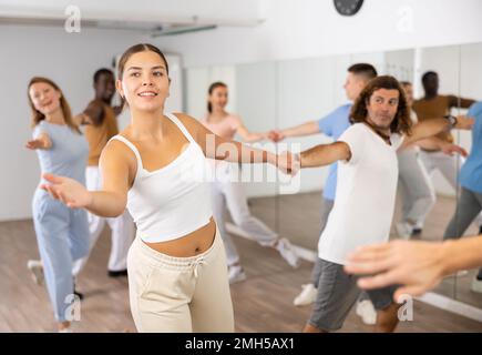Smiling young adult couples dancing together in pairs and practicing movements in modern choreography class Stock Photo