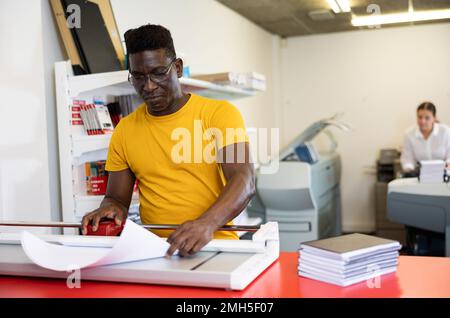 Employee of printing house checks the quality of printing in computer room Stock Photo
