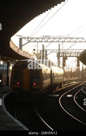 Northern trains express sprinter dmu waiting in Carnforth railway station on 25th January 2023 with evening sunlight glinting off side of two car unit. Stock Photo