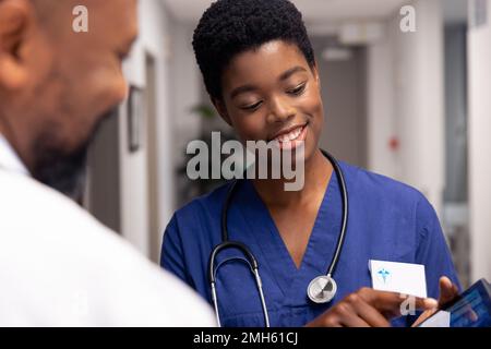 Smiling african american male and female doctor using tablet in hospital corridor Stock Photo