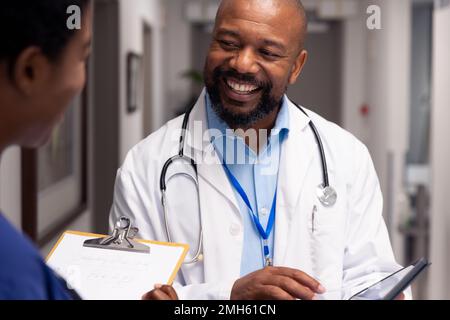 Smiling african american male and female doctor talking in hospital corridor Stock Photo
