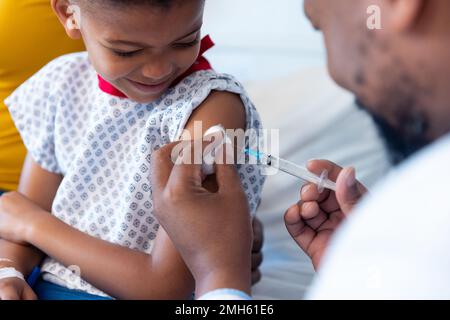 African american male doctor vaccinating a boy patient in hospital Stock Photo