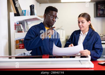 Cheerful multiracial coworkers checking the print quality and accepting color proofs in the printing house Stock Photo
