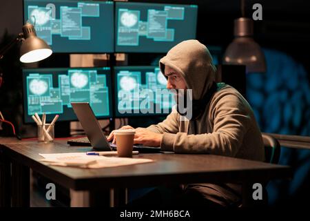 Hacker stealing computer information from server, cybercrime threat and security breach on multiple monitors. Programming virus and hacking big data hardware, man wearing hood. Stock Photo