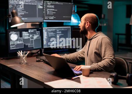 Software developer coding database on multiple monitors to program new server interface at night. Workign after hours to develop html source code on terminal window, artificial intelligence. Stock Photo