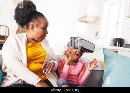 Happy african american grandmother and granddaughter using vr headset in living room Stock Photo
