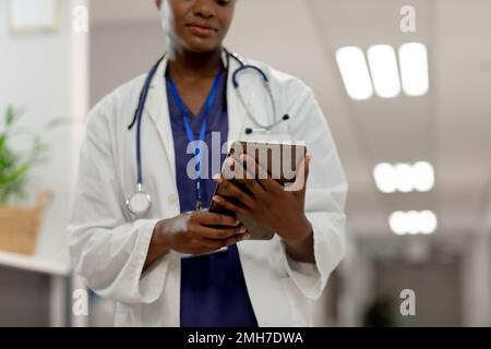 African american female doctor working at hospital, using tablet Stock Photo