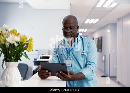 African american male doctor working at hospital, using tablet Stock Photo
