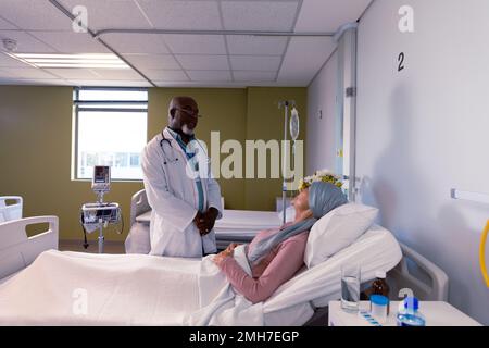 African american male doctor visiting senior caucasian female cancer patient in head scarf Stock Photo