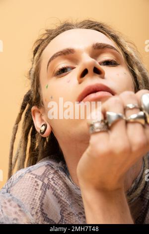 Low angle view of tattooed nonbinary person looking at camera isolated on yellow,stock image Stock Photo