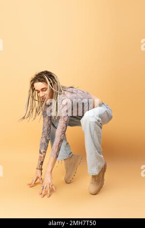 Cheerful queer person with dreadlocks posing on yellow background,stock image Stock Photo