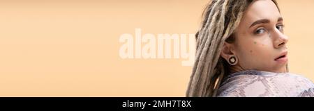 Young nonbinary person with dreadlocks looking at camera isolated on yellow, banner,stock image Stock Photo