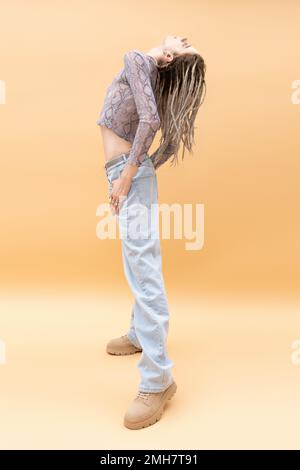 Side view of stylish queer person with dreadlocks posing on yellow background,stock image Stock Photo