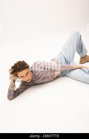 Queer person with dreadlocks lying on white background,stock image Stock Photo