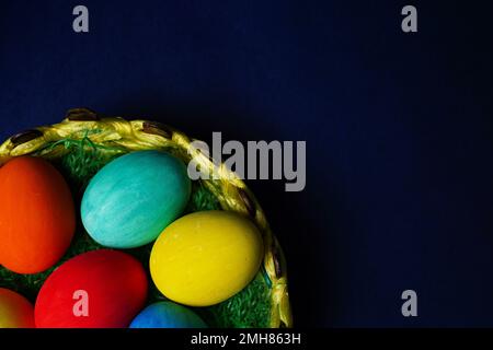Easter composition with colorful eggs in basket on blue background. Stock Photo