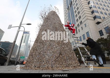 A member of Korean Federation for Environmental Movement in a Santa Claus  outfit attaches cigarette butts at a cigarette butt Christmas tree in front  of Korea Tobacco & Ginseng Corporation office in Seoul, South Korea,  Monday, Dec. 23, 2019. The 