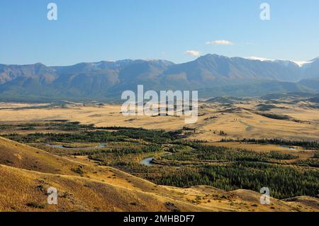 High mountains on the edge of the steppe and a winding river flowing through the valley on a sunny autumn evening. Kurai steppe, Altai, Siberia, Russi Stock Photo