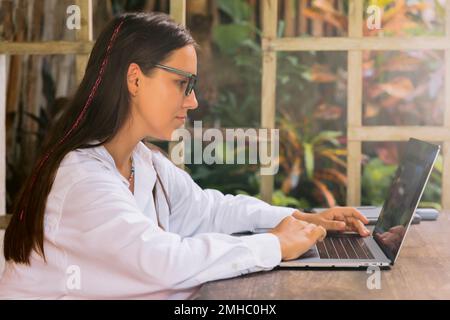 Attractive young woman typing on laptop computer in summer cafe Stock Photo
