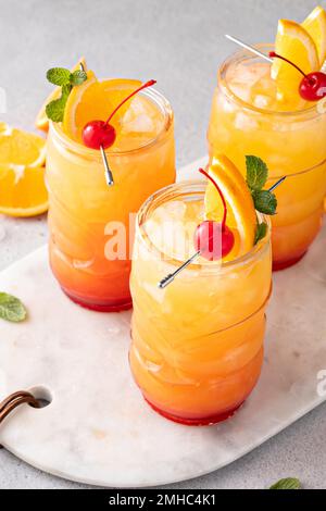 Rum punch in tiki glasses with orange slices and a cherry Stock Photo