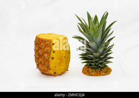 pineapple with half of the peel peeled and the crown removed on a white background Stock Photo