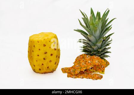peeled pineapple with the crown and the peel placed next to it on white background Stock Photo