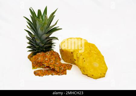 peeled and chipped pineapple with the peel and the crown on the side on a white background Stock Photo