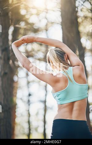 Sore today strong tomorrow. Rearview shot of a young woman stretching her arms outdoors. Stock Photo