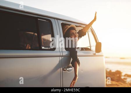 Where Im free to be me. a young woman leaning out of her vans window with her arms outstretched. Stock Photo