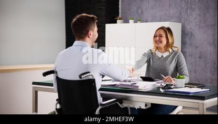 Business Man In Wheel Chair Shaking Hand In Office Stock Photo