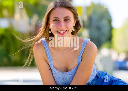 Close Up of Teenage Girl Smiling Sitting and Leaning Towards Camera on Concrete Steps of Palo Alto City Hall Plaza Stock Photo