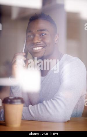I know just the place for the next coffee date...a handsome young man using his phone while sitting in a cafe. Stock Photo