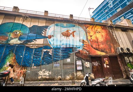 A large mural on the side of a supermarket, depicting a blue bird and orange cat looking at a goldfish in a fishbowl. An example of graffiti in Naples Stock Photo