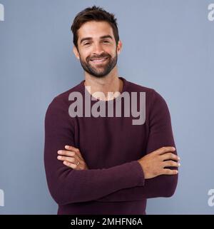 Confidence sure looks good on him. Studio shot of a handsome and confident young man posing against a gray background. Stock Photo