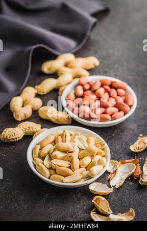 Unpeeled and peeled peanuts in bowl on the kitchen table. Stock Photo