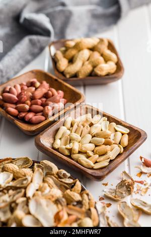 Unpeeled and peeled peanuts in bowl on the kitchen table. Stock Photo