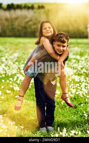 Big brothers are the best. Portrait of an adorable little boy giving his little sister a piggyback ride outside. Stock Photo