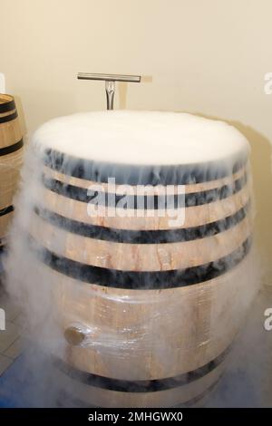 wood barrel in cellar white smoke dry ice in harvest wooden barrels for refresh grapes during fermentation Stock Photo