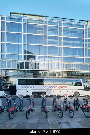 A coach and hire bicycles parked outside 151 HUB Victoria, an office building on Buckingham Palace Road, London, England. Stock Photo